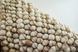 Full view of natural beige pebble wool rug on wood floor