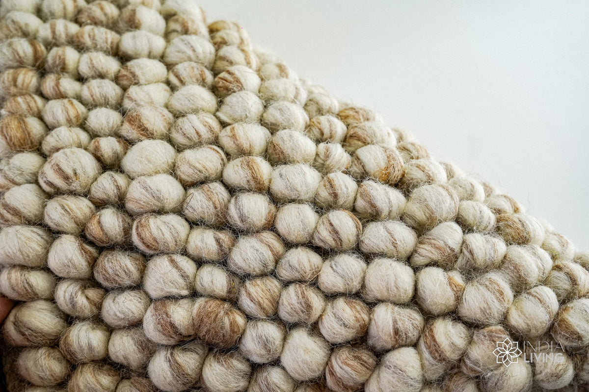 Full view of natural beige pebble wool rug on wood floor
