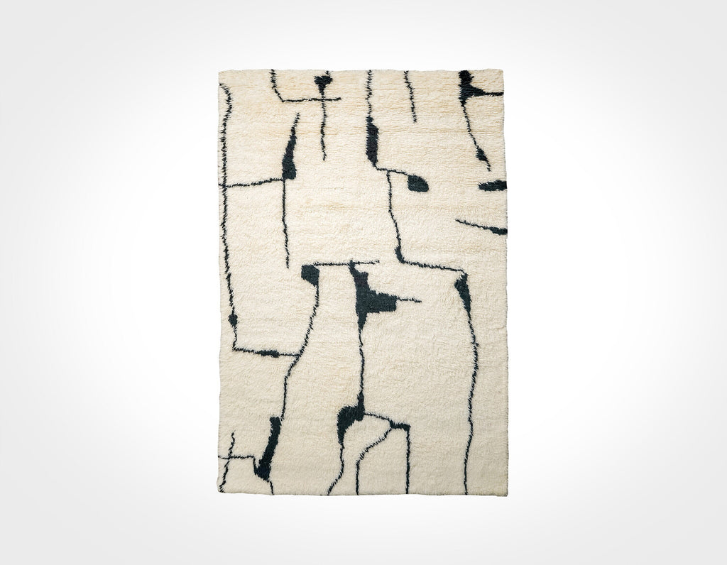 May include: A white rug with a black abstract design. The design is made up of lines and shapes that resemble a maze or a network of paths.