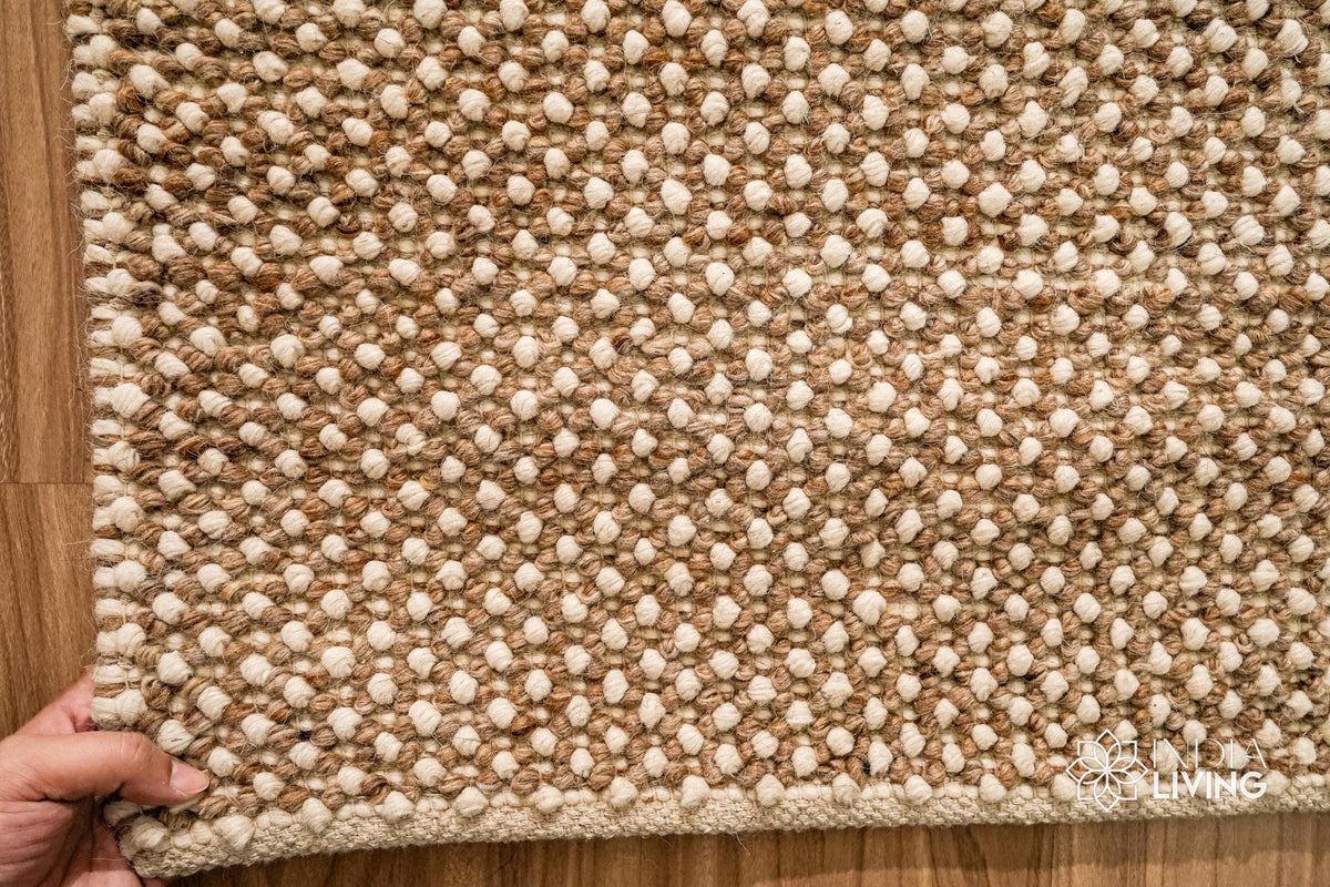 Beige wool rug styled in a bedroom