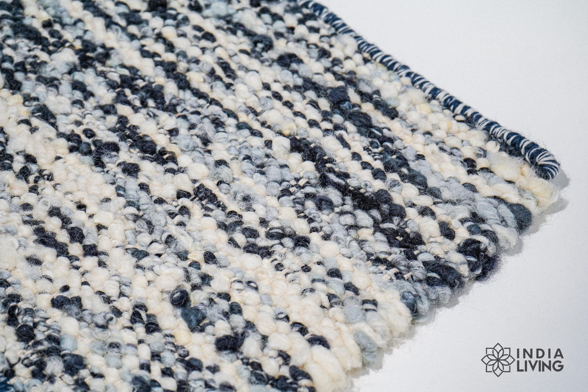 Full view of ivory blue textured wool rug on floor
