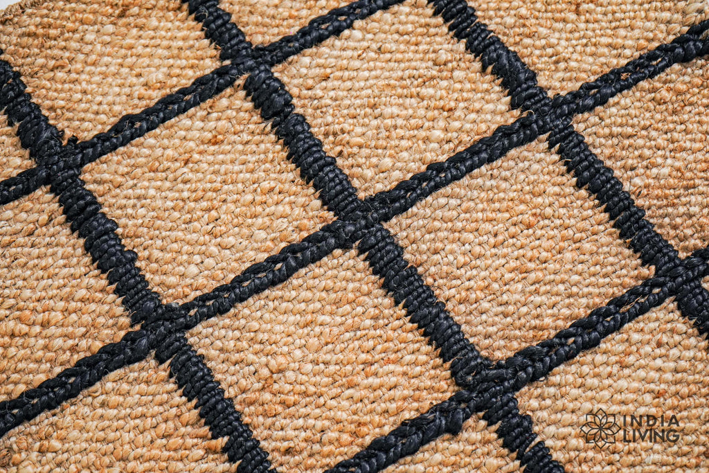 May include: Close-up of a woven jute rug with black stripes. The rug has a natural, earthy texture and is perfect for adding a touch of rustic charm to any room.