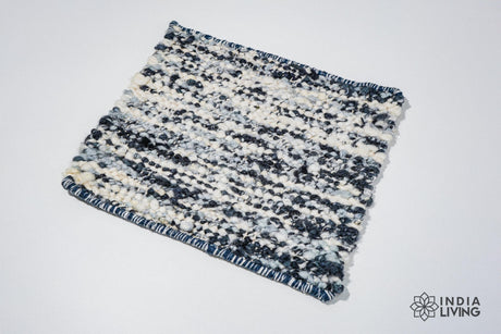 May include: A small, rectangular rug with a blue and white woven design. The rug has a fringed edge and is made of a soft, textured material.