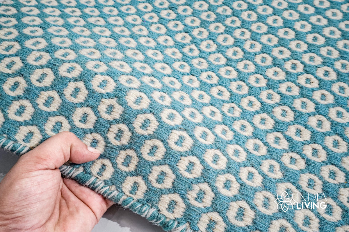 Turquoise blue flatweave rug in a bright bedroom setting