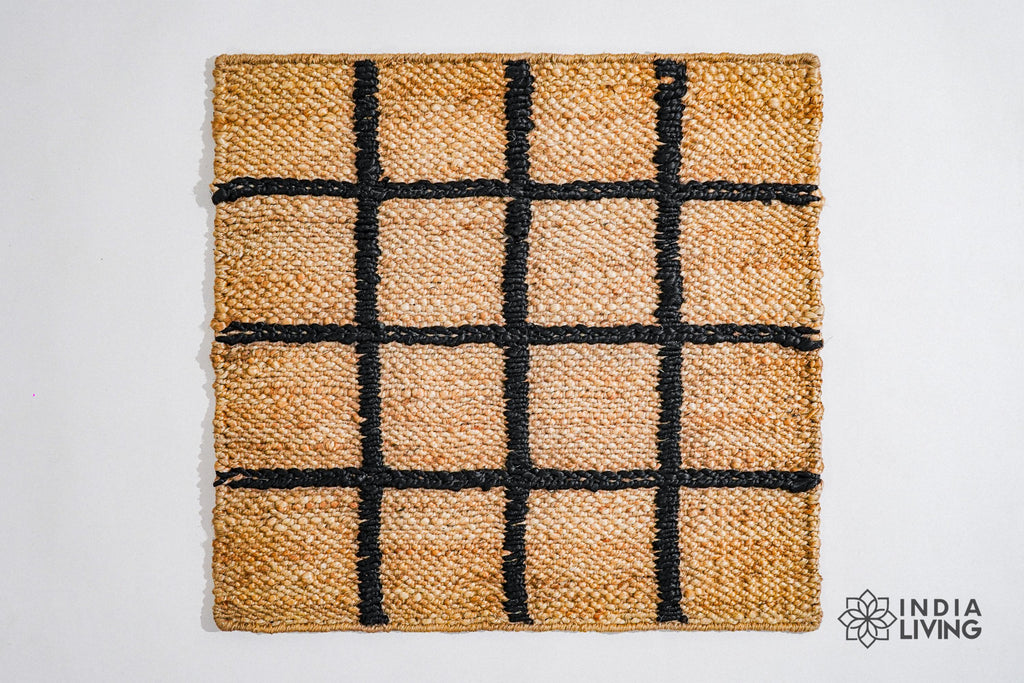 May include: A square jute rug with a black and tan color scheme. The rug has a grid pattern with black lines woven into the tan jute fabric.
