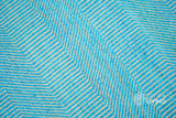 Aqua blue wavy stripe flatweave rug in a coastal-style bedroom