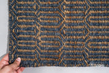 Bluish grey geometric rug corner detail showing edge binding