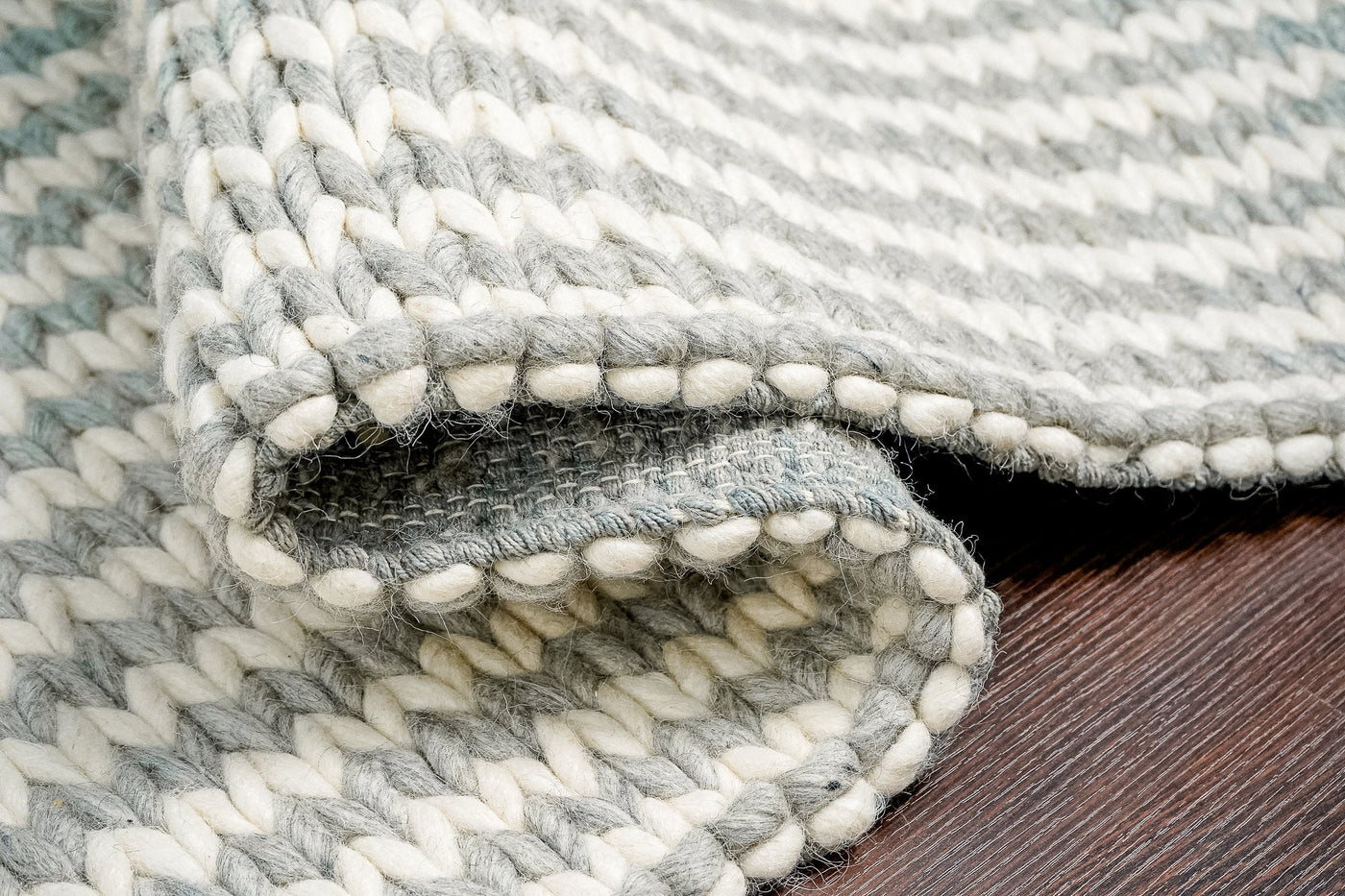 Grey ivory chunky braided wool rug folded flat, showing braided texture detail