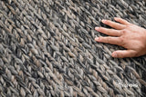 Handwoven chunky wool rug shown in a cozy bedroom setting