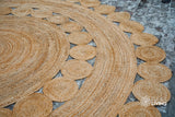 Round hand braided natural jute rug with medallion design, flat view