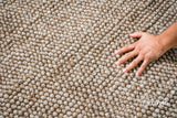 Beige chunky wool rug folded to show reversible construction