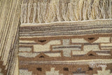 Close-up of fringe and knotted braid detail on beige kilim rug