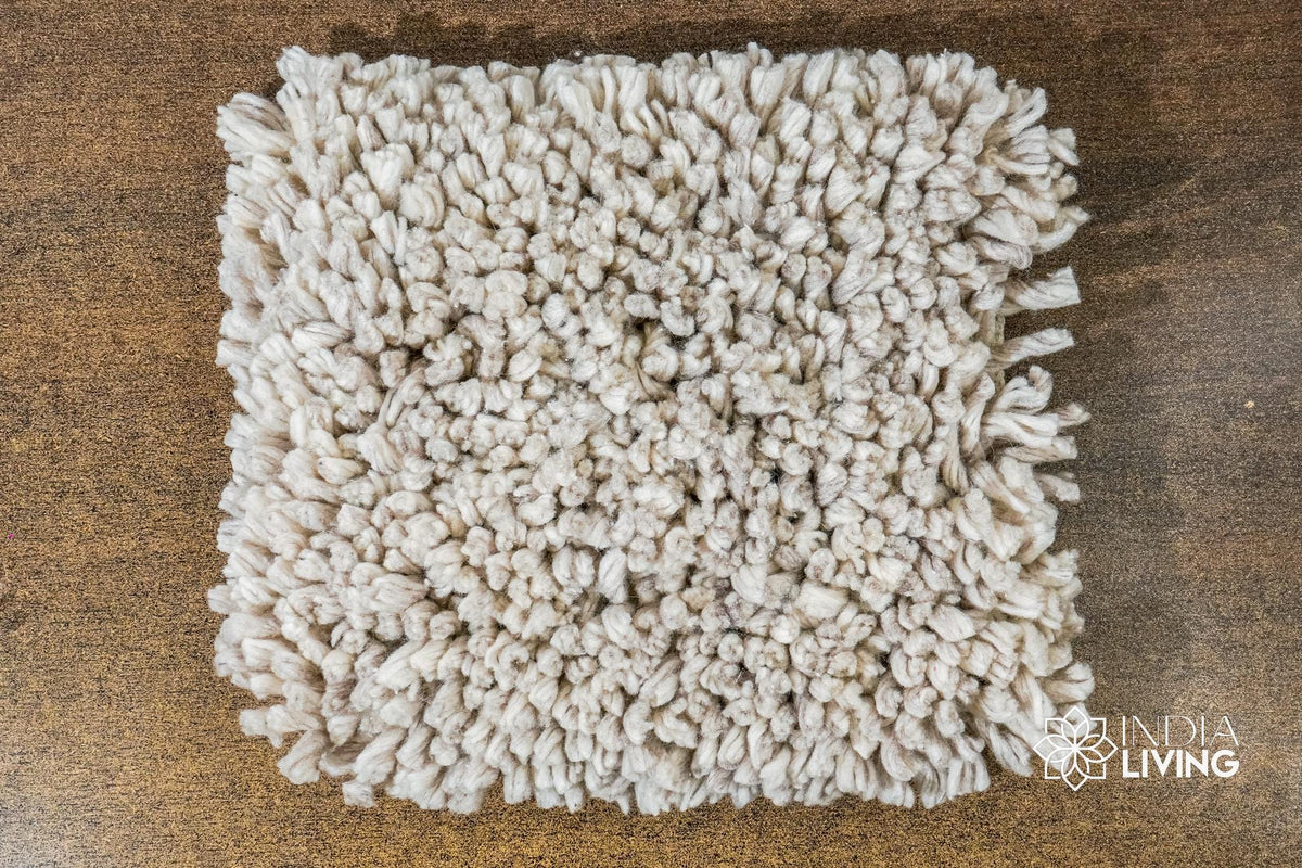 Corner view of taupe grey wool shag rug showing pile depth