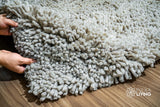 Taupe grey wool shag rug edge close-up highlighting knotted pile